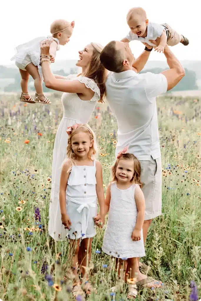 Matthew Roda and his family posing for family portraits in an open flower field